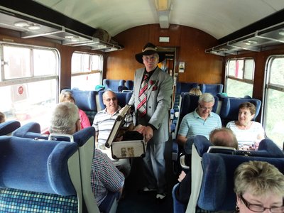 Spiv on the train trying to sell John some contraband ladies underwear