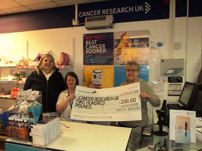 Staff at the Boston Cancer Research UK Charity Shop receive the cheque for £200 raised by Lincolnshire MGF/TF Register over 2014